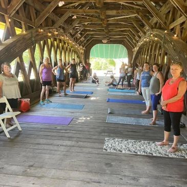 A group of women taking a barre class in a covered bridge during a pop up class sponsored by A Bette