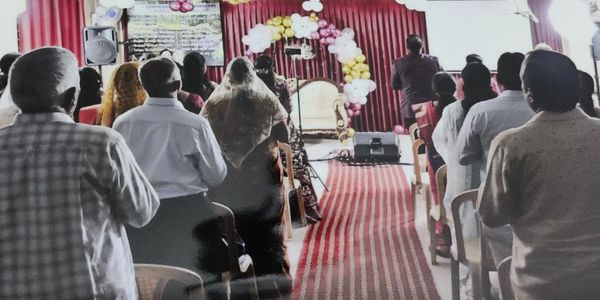 People attending a formal indoor event with balloon decorations and a red carpet.