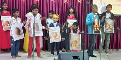 Children performing a school play with vessel-themed posters on stage.
