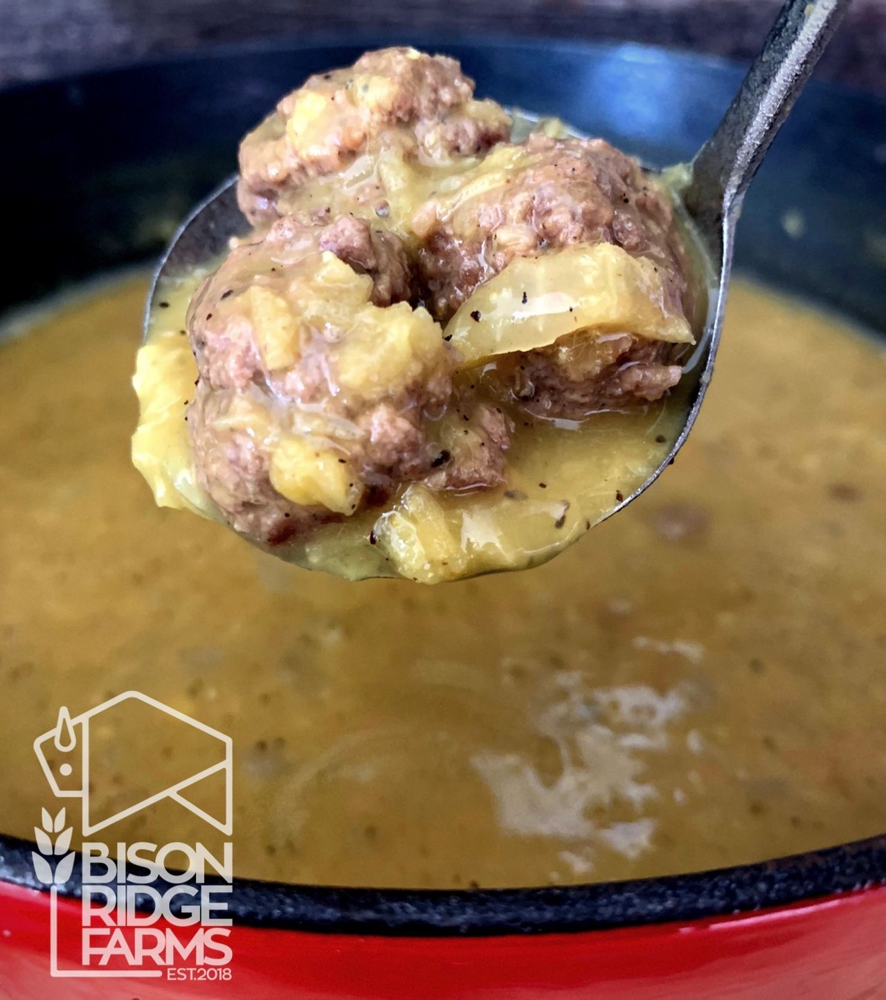 Ladle full of red lentil soup with bison meatballs