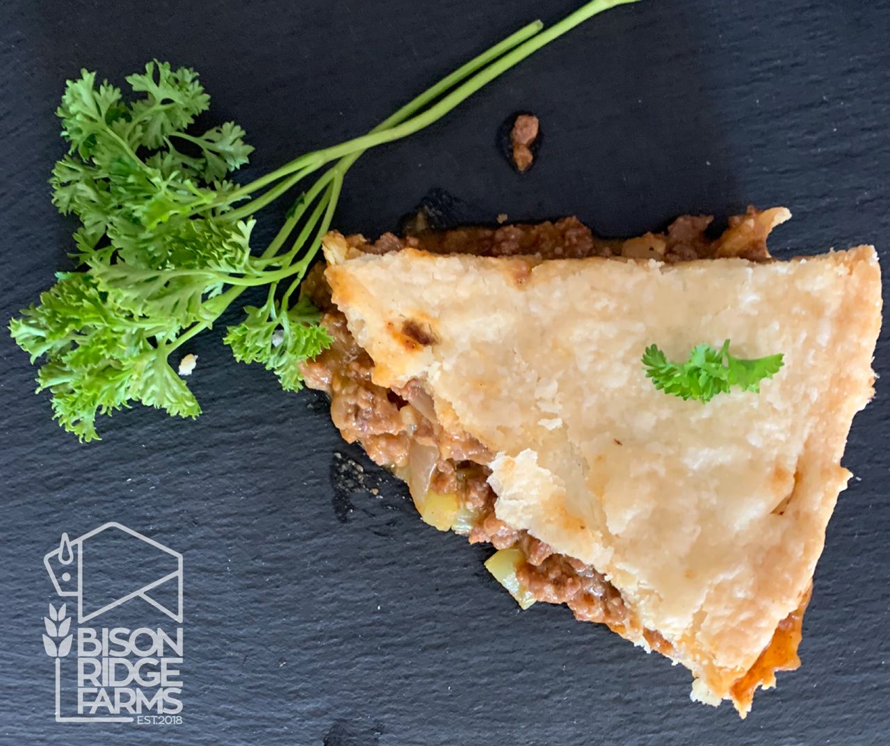 Slice of bison and cheddar pie garnished with parsley