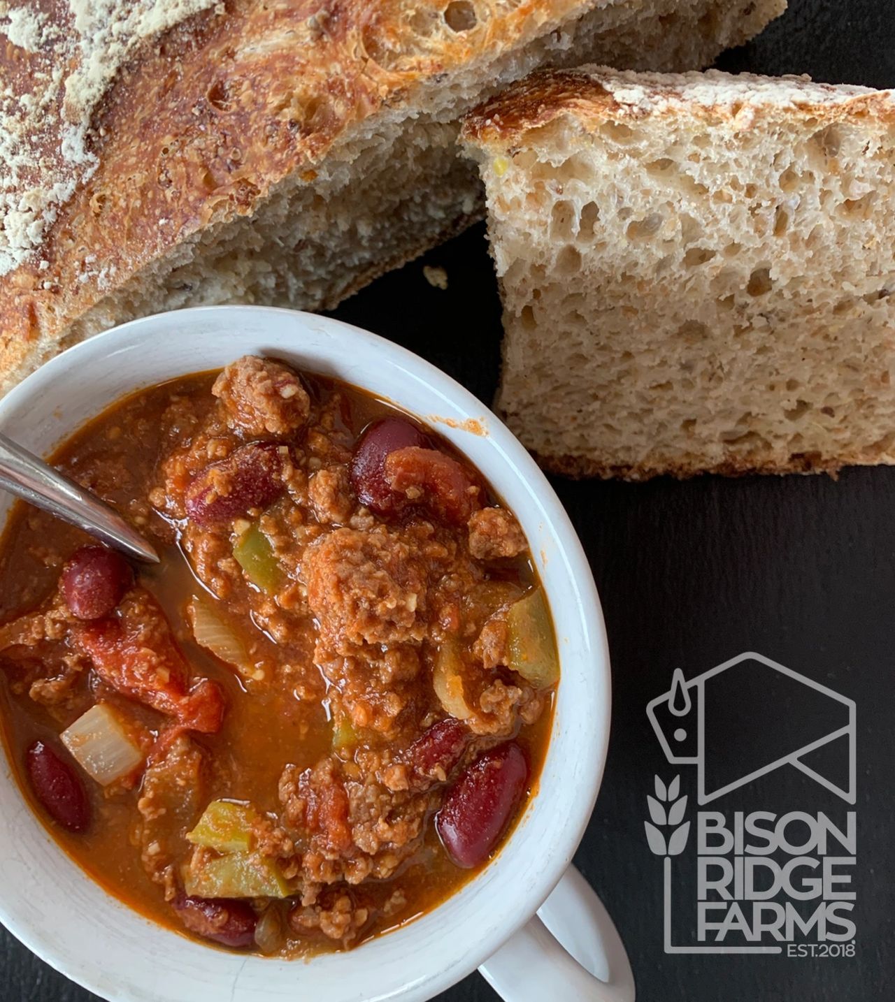 Bison chili in a large soup mug with a side of whole wheat bread