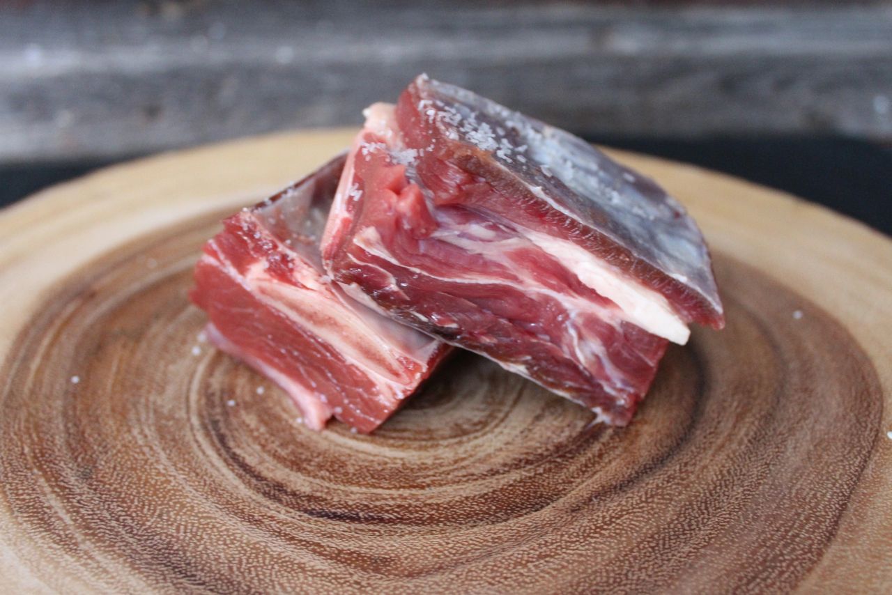 Raw bison short ribs on live edge cutting board