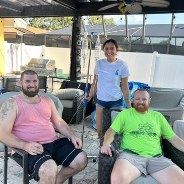 Three friends relaxing outdoors with a golf putter, smiling for the camera.