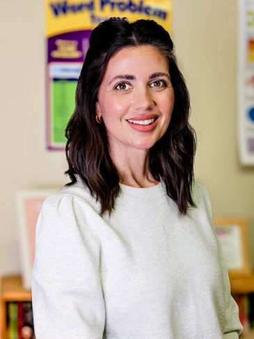 Smiling woman in a white sweater in an educational setting.