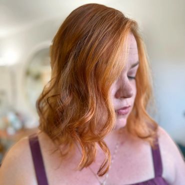 Woman with wavy red hair wearing a purple top.