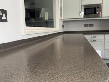 A clean, modern kitchen countertop with light-colored cabinets and a microwave.