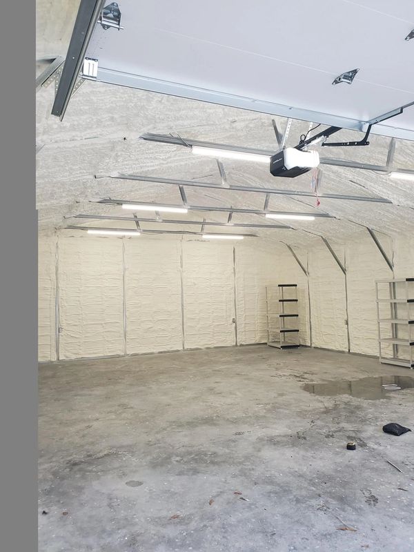 Empty insulated garage with metal shelves and fluorescent lights.