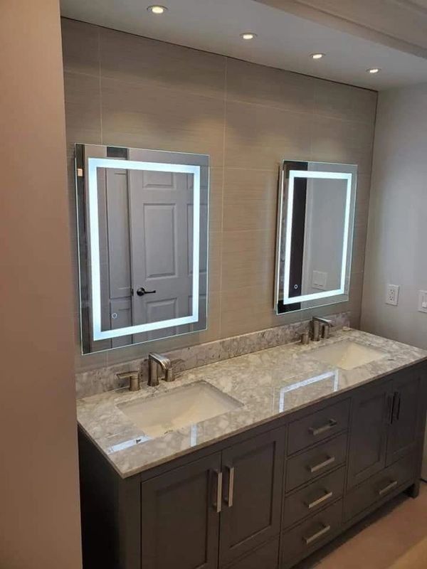 Modern bathroom with dual sinks and illuminated mirrors.