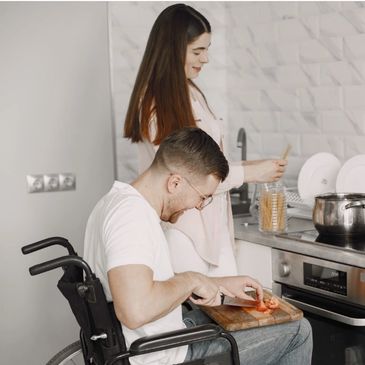 Little Light daily living support: a man using a wheelchair preparing vegetables alongside a woman i