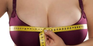Woman measuring her breast size for a breast reduction