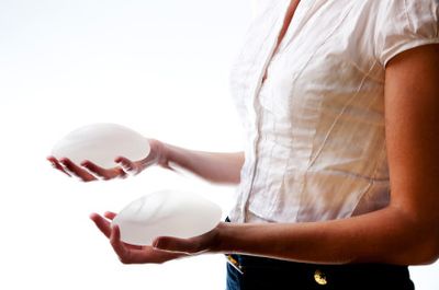 Woman holding two silicone gel breast implants