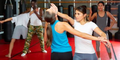 Women practicing self-defense techniques in a gym.
