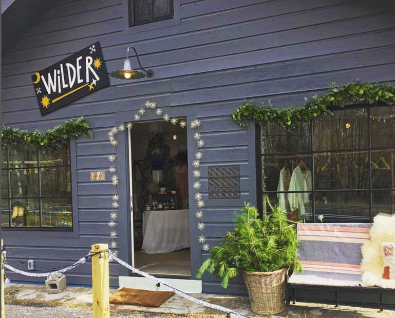 Purple shop exterior with greenery and bench.
