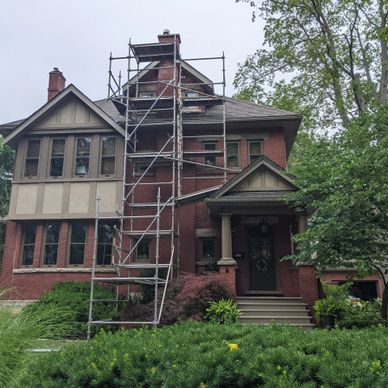 Old brick house with scaffolding for repairs on the roof.