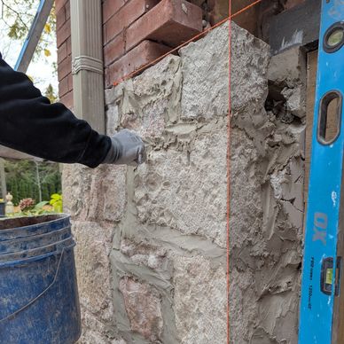 Worker applying mortar to stone wall for construction.
