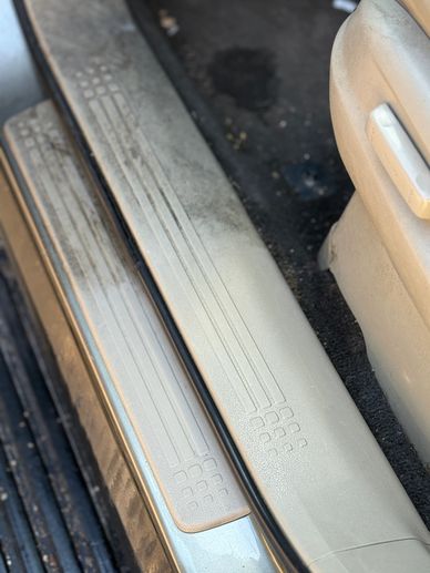Close-up of a dirty car door sill and floor mat.