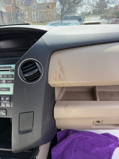 Interior of a car showing dashboard and glove compartment with visible stains.
