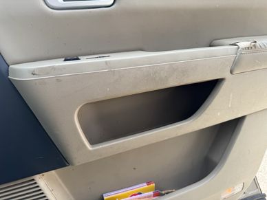 Close-up of a car door panel with storage compartments and some dirt marks.