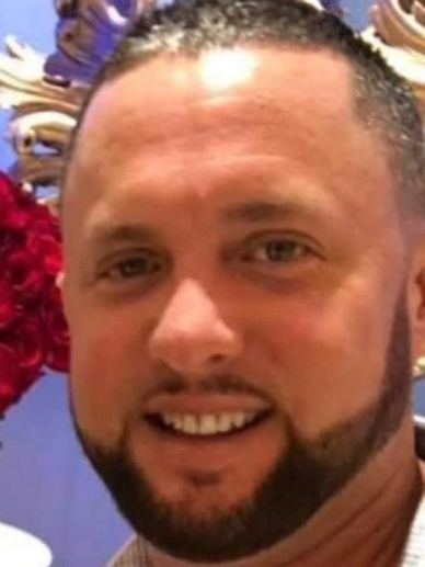 A smiling man with a trimmed beard and short hair.