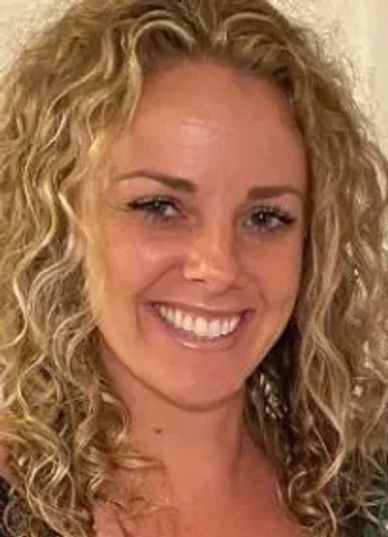 Smiling woman with curly blonde hair.