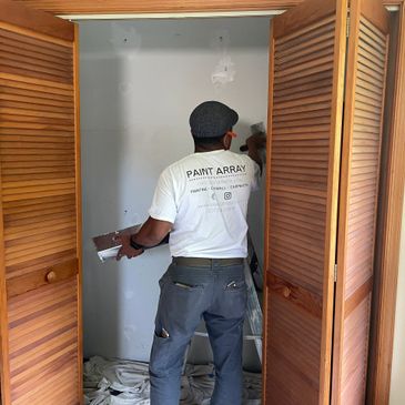 Paint Array owner Teito Amador working on fixing drywall in a bedroom closet. 