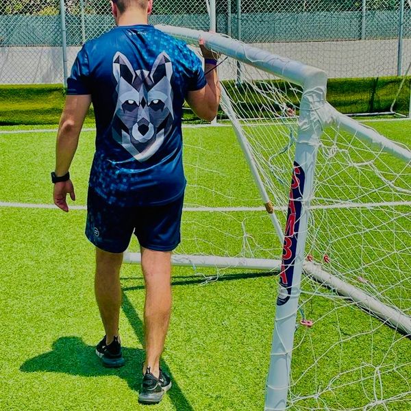 Coach carrying a football goal, with Ballin Out wolf t shirt logo