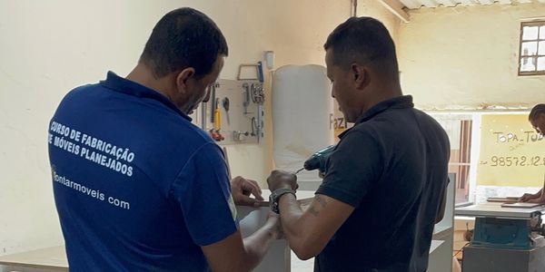 Two men working together on a woodworking project indoors.