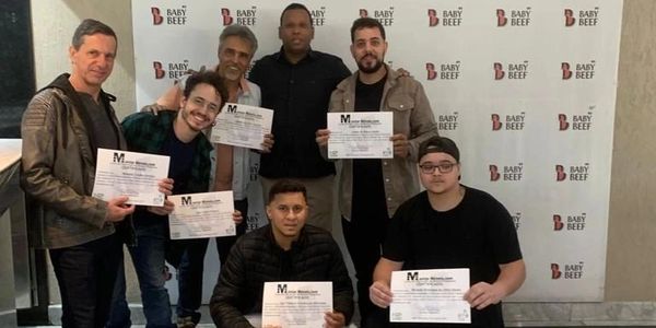 Group of seven men holding certificates in front of a Baby Beef backdrop.