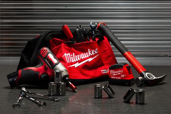 A Milwaukee tool bag with various red and black tools displayed on a metal surface.