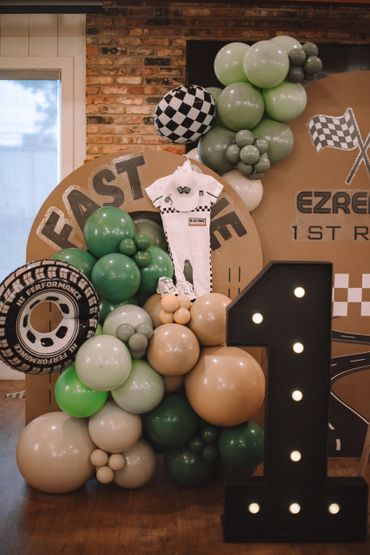 A racing-themed first birthday party setup with balloons and a racing outfit.