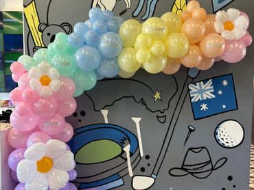 Colorful balloon arch with positive words and flower shapes in front of a playful mural.