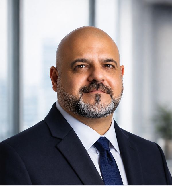 Confident man in suit with a beard and tie in an office setting.