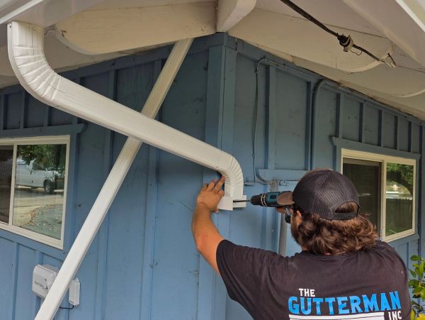 Man fixing a gutter on a blue house.