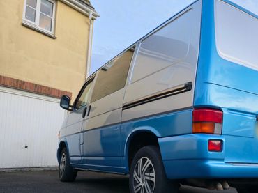 Blue and white van parked beside a house with garage.