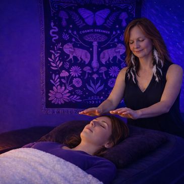 A woman receives a calming energy healing session in a serene room.