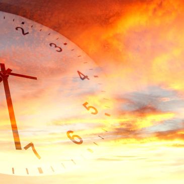 Clock face overlaying a vibrant sunset sky.