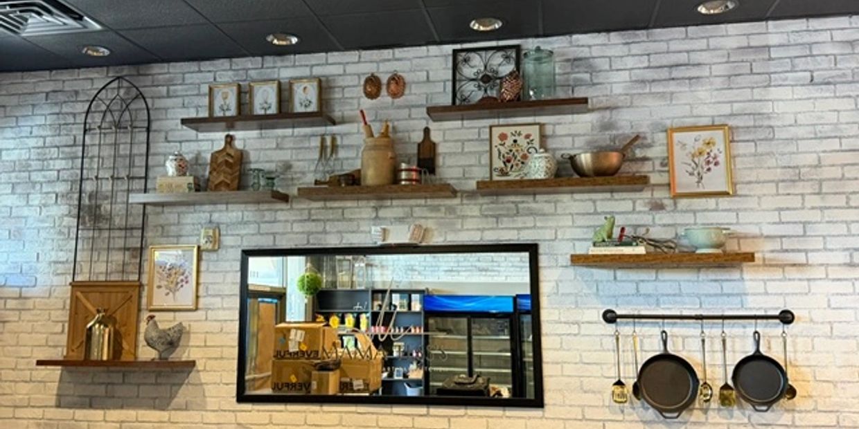 Wall with shelves holding kitchen decor and a mirror reflecting a rustic interior.