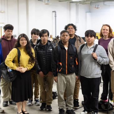 A diverse group of young adults standing indoors, facing the camera.