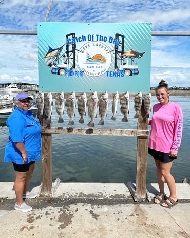 Two women proudly display their catch of fish at a Texas harbor.