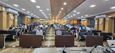 Audience seated in a large conference room facing the camera.