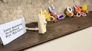 Children's Easter decorations displayed on a wooden shelf at Bryn Offa School.