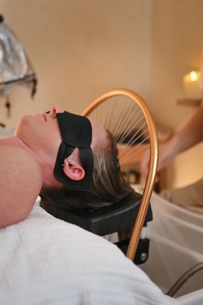 Person with blindfold relaxing on a chair, possibly receiving a treatment.