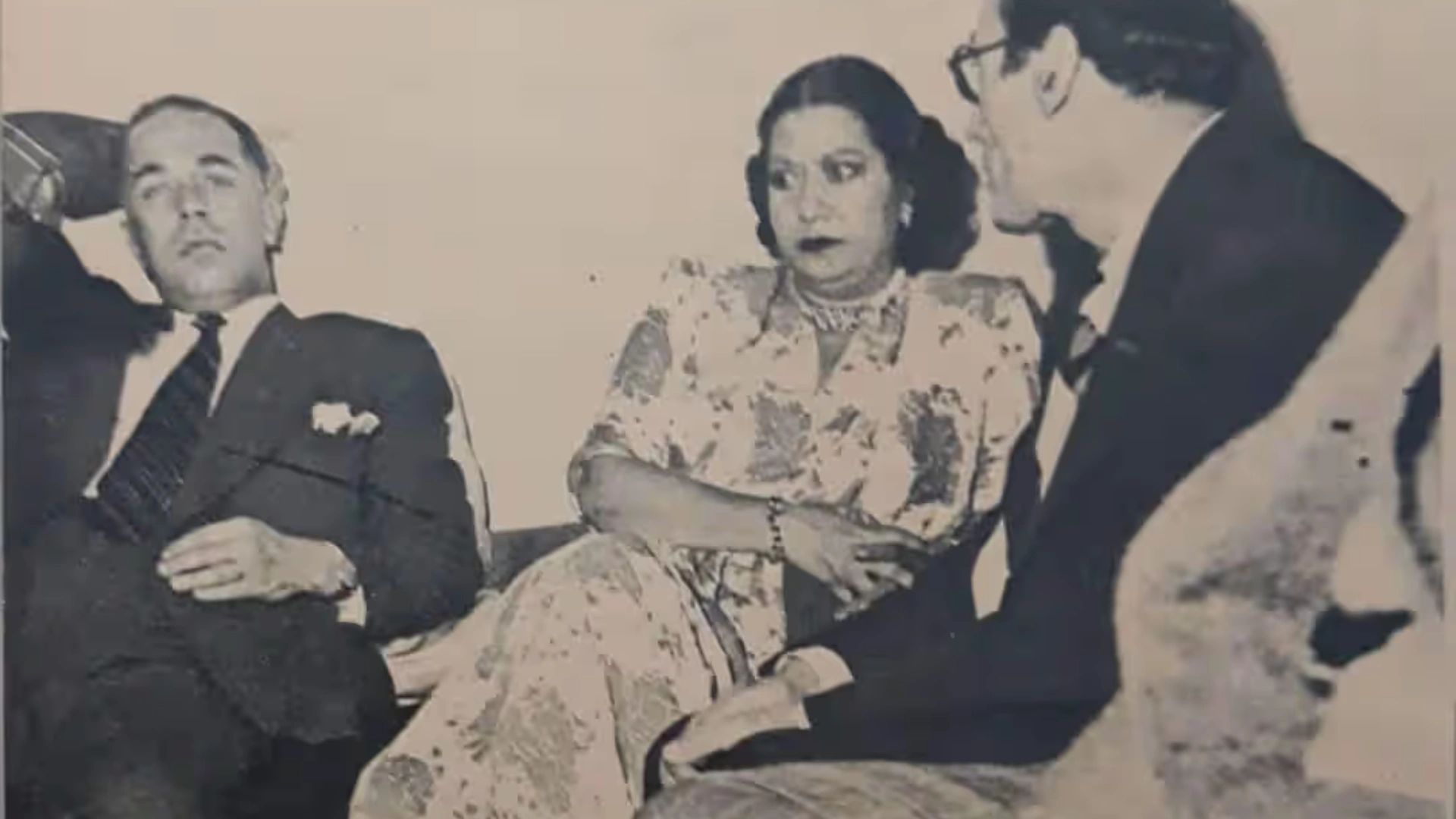 Three people in formal attire engaging in a serious conversation.
