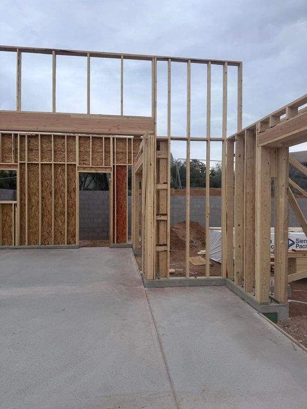 Wooden frame structure under construction on a concrete foundation.