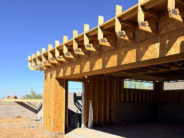 Wooden framing of a building under construction on a clear day.