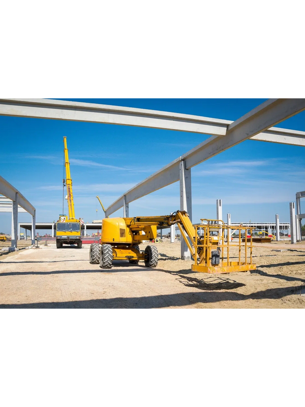 Yellow construction machinery at an industrial site under a clear blue sky.