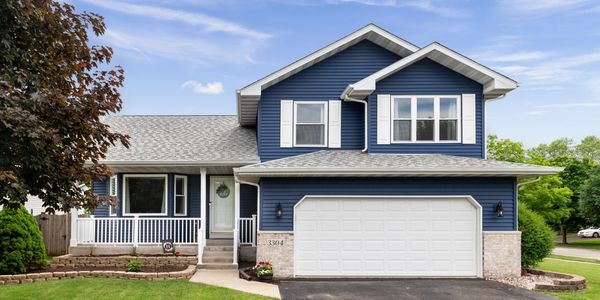 A blue two-story house with white trim and a white garage door, featuring a well-maintained lawn.