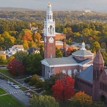 Clock tower on a college campus surrounded by fall foliage.