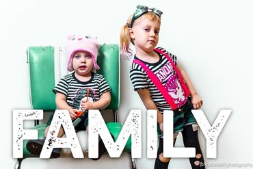 Two little girls posting in black stripes with pink accents and a teal chair 